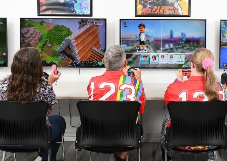 Three people playing Nintendo Switch on two TV's